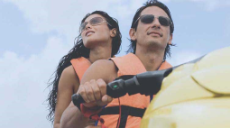 With orange life vests, a couple enjoy a day on a jet ski.